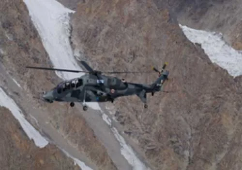 Indian Air Force helicopter (LCH Prachand) flying low over snow-streaked mountainous terrain