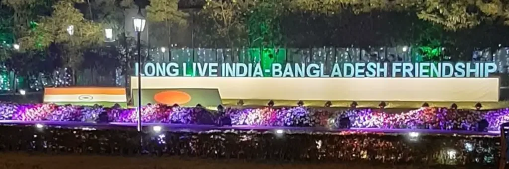 Illuminated "Long Live India-Bangladesh Friendship" sign with the Indian and Bangladeshi flags lit up at night